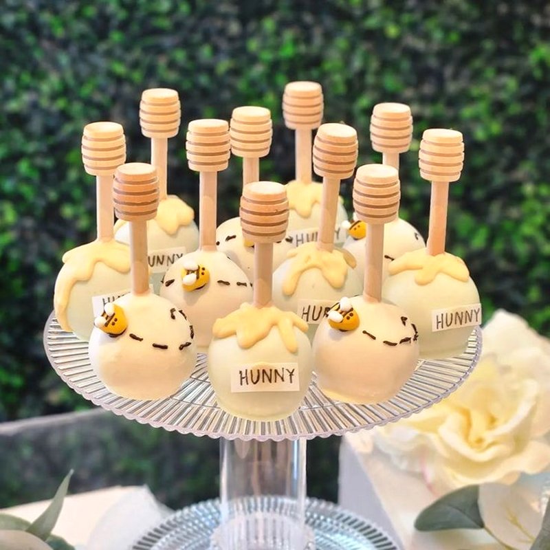 Bumble bee cake pops with bees and hunny signs attached to honey stirrers - perfect desserts for Mommy to Bee + Winnie the Pooh baby showers