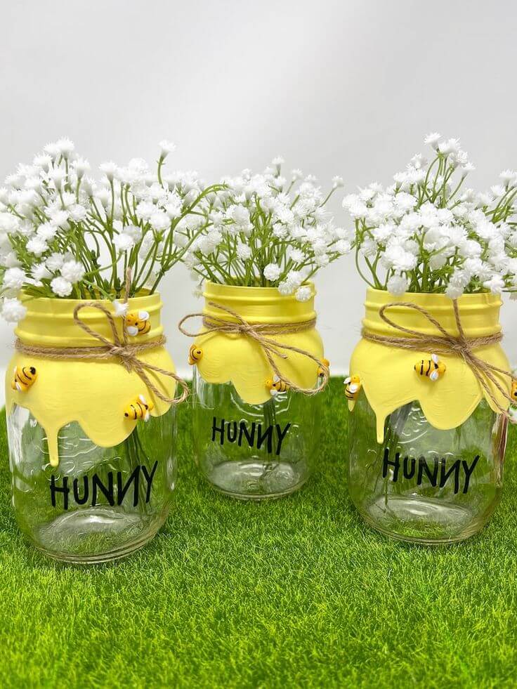 Cute baby shower centerpieces feature mason jars filled with baby's breath and bumble bees - great Winnie the Pooh and bee baby shower ideas