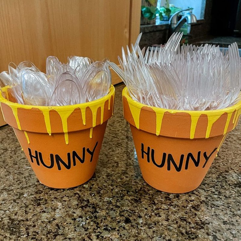 Winnie the Pooh theme decor idea - Terracotta clay pots decorated with word Hunny hold utensils for Winnie the Pooh baby shower food table