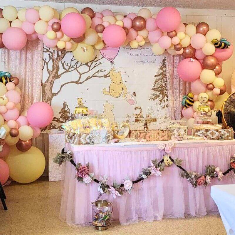 Winnie the Pooh Baby shower decor, featuring pink balloon arch and Pooh inspired decorations for a girl baby shower